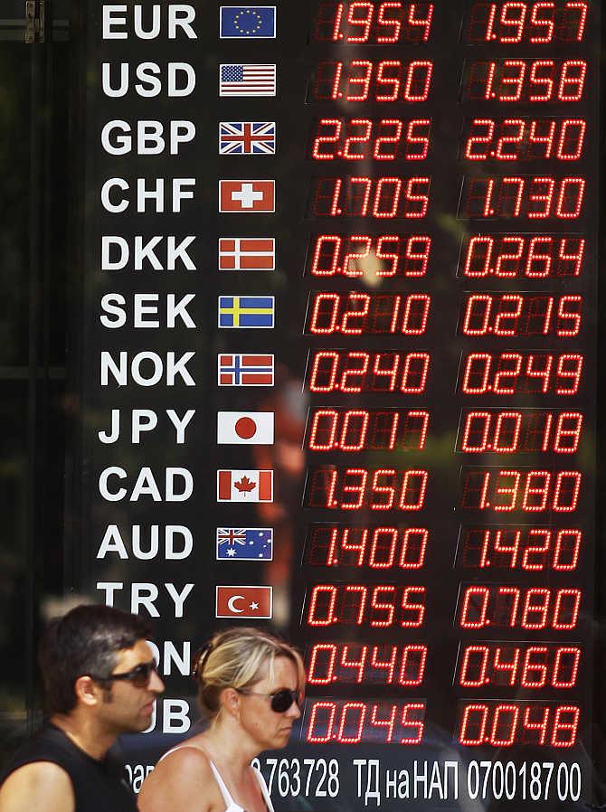 People walk past a display board of a currency exchange office in Sofia, Bulgaria.