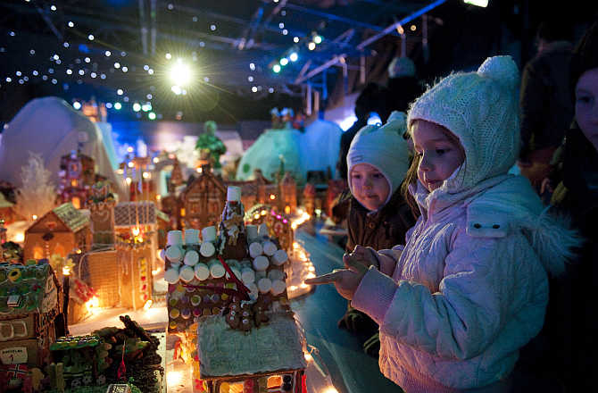 Children look at a gingerbread town consisting of buildings, boats, bridges and other structures, in Bergen, Norway.
