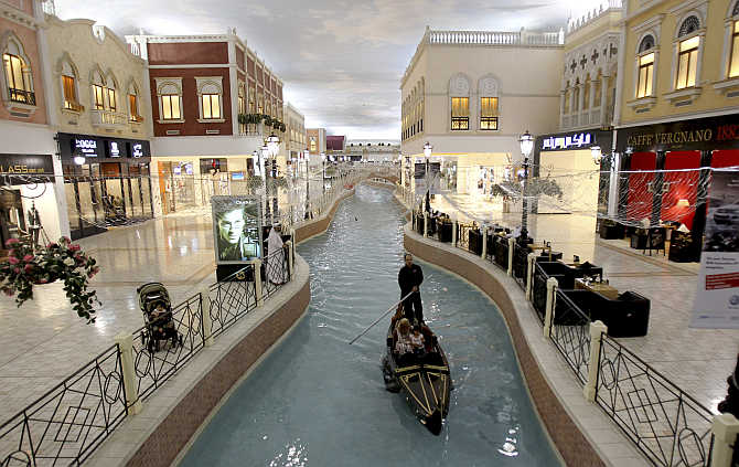 A family takes a sampan ride on a canal inside Villagio Mall, a popular shopping area in Doha, Qatar.