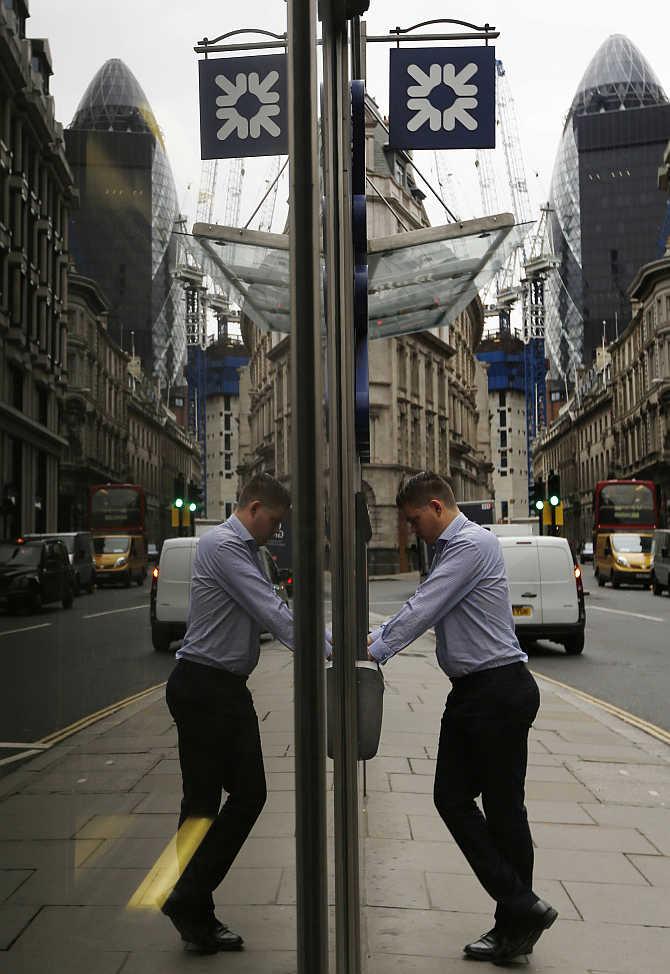 A man uses a cash machine outside a branch of Royal Bank of Scotland in London.