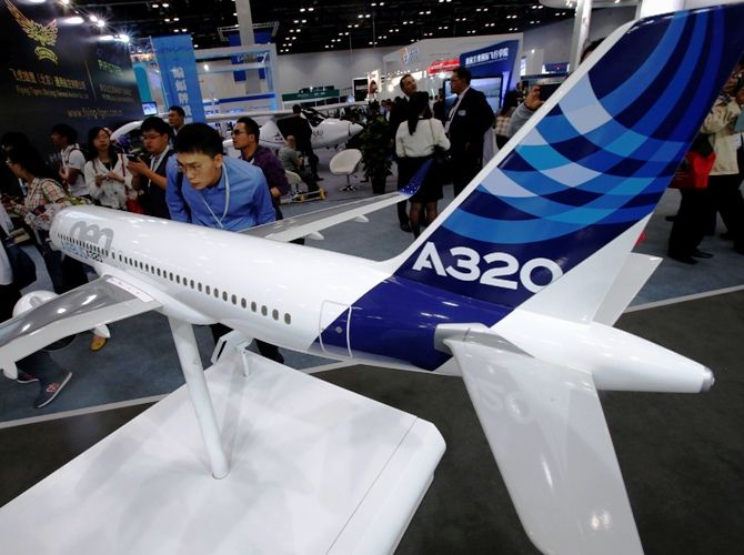 A visitor looks at a miniature model of an Airbus A320 at an Aviation Expo