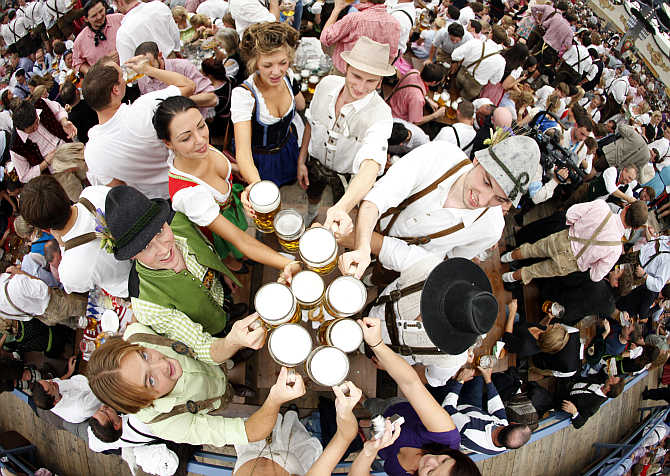 People toast with beer mugs at the Oktoberfest in Munich, Germany.