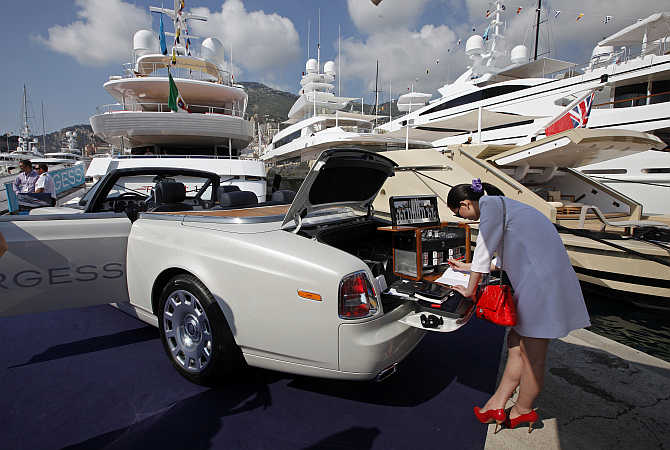 A visitor is seen next to a Rolls Royce parked on Monaco port.