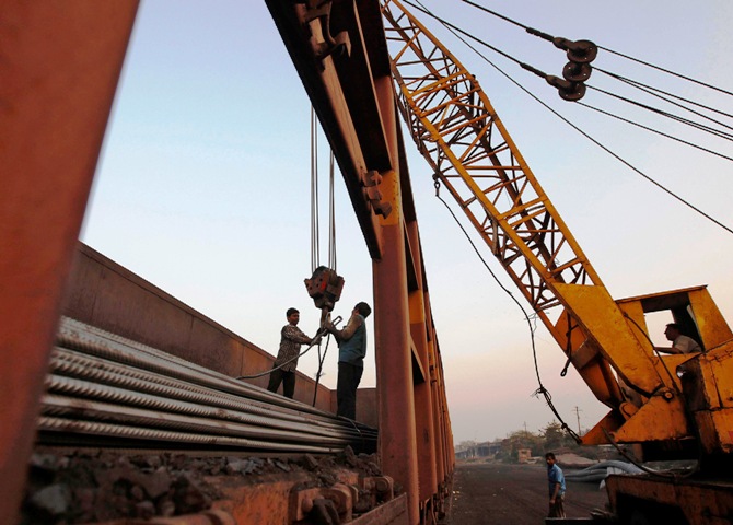 Workers prepare to unload steel rods with a crane from a goods train at a railway yard in Ahmedabad.