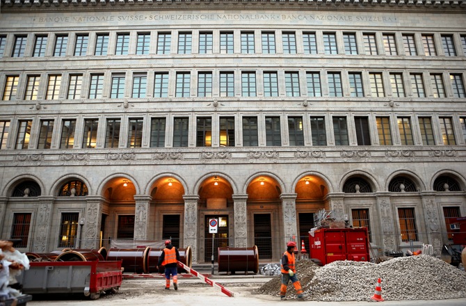Workers stand at a construction site in front of the Swiss National Bank (SNB) in Zurich.