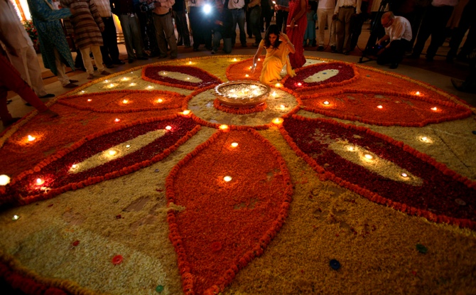 A woman lights up lamps in a flower decoration during Diwali mahurat special trading on the occasion of Diwali.