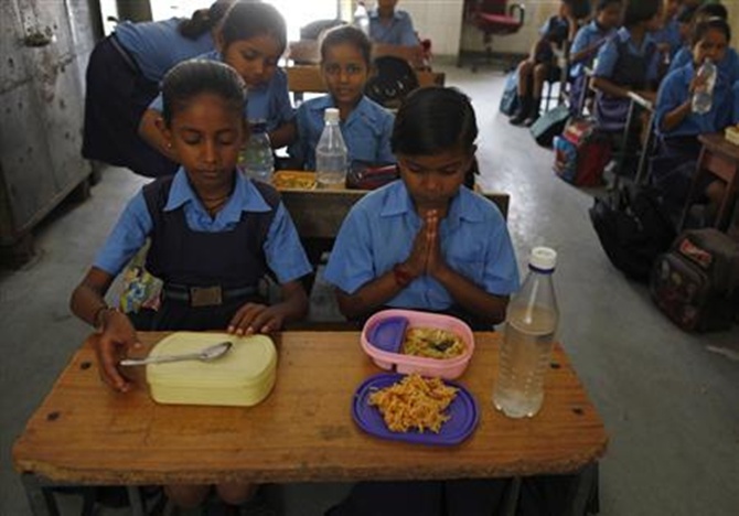 A schoolgirl (C) prays before having her free mid-day meal, distributed by a government-run primary school, in New Delhi.