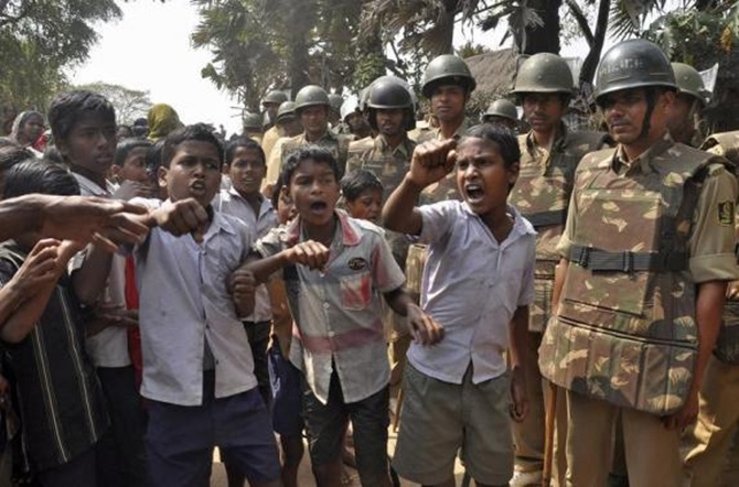 Children shout slogans as police stand guard during a protest against land acquisition at Gobindpur village in Jagatsinghpur district in Odisha.