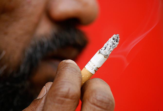 A man smokes a cigarette on a pavement in Siliguri. 
