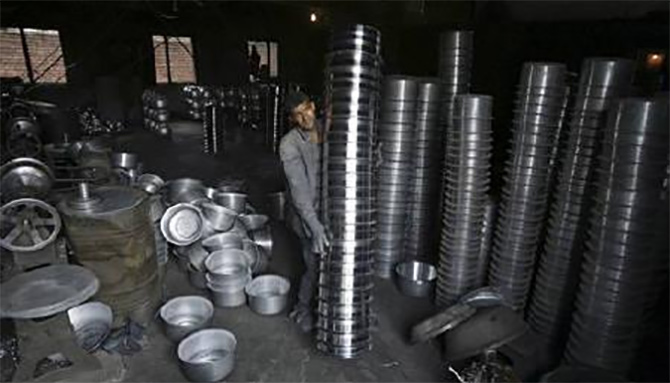An employee works inside an aluminium utensil manufacturing unit.