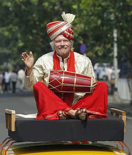 Virgin Group founder Richard Branson plays a dhol while sitting atop a taxi during a promotional event in Mumbai.