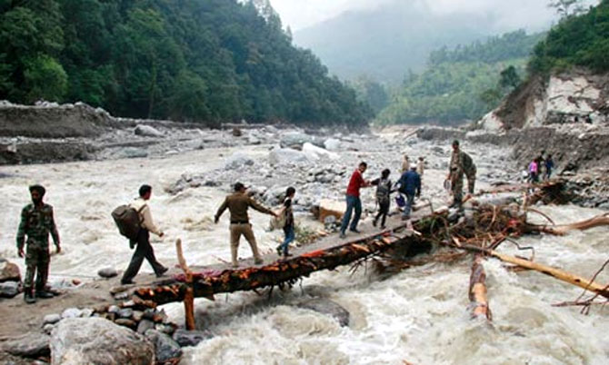 File photo of rescuers helping stranded people cross a flooded river in Uttarakhand.