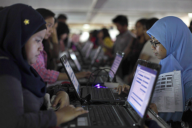 Job seekers apply for jobs using computers as they visit a job fair in Jakarta.