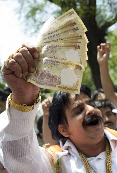 A man hands out money as supporters celebrate election results in front of the headquarters of the Congress Party.