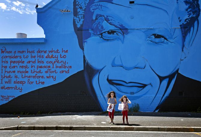 India Harris, age eight, and her sister Kitty, five, stand in front of a Nelson Mandela wall mural.