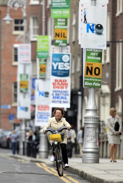 A woman cycles past posters in central Dublin.
