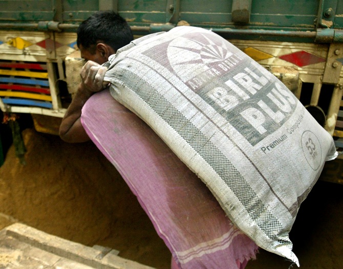 This file photograph shows an Indian labourer carrying a Birla cement sack in front of a whole sale store.