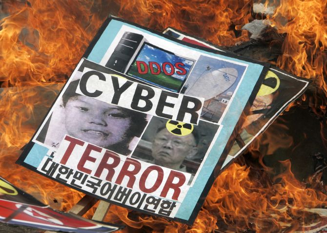 Conservative protesters burn portraits of North Korea's Kim Jong-il (R) and his son Kim Jong-un during an anti-North Korea rally denouncing the North's cyber attacks.
