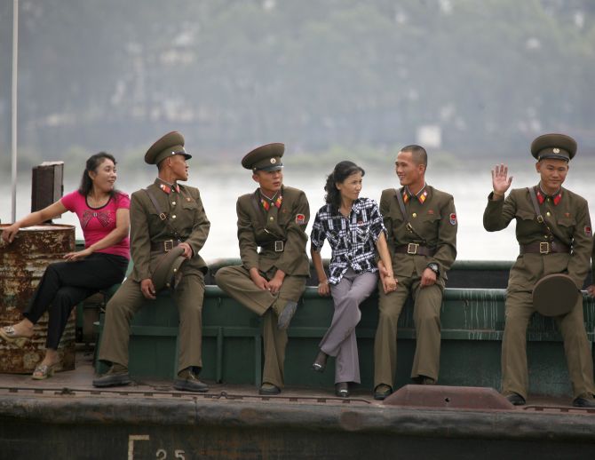 A North Korean soldier waves to a Chinese tourist boat on the Yalu River near the North Korean town of Sinuiju.