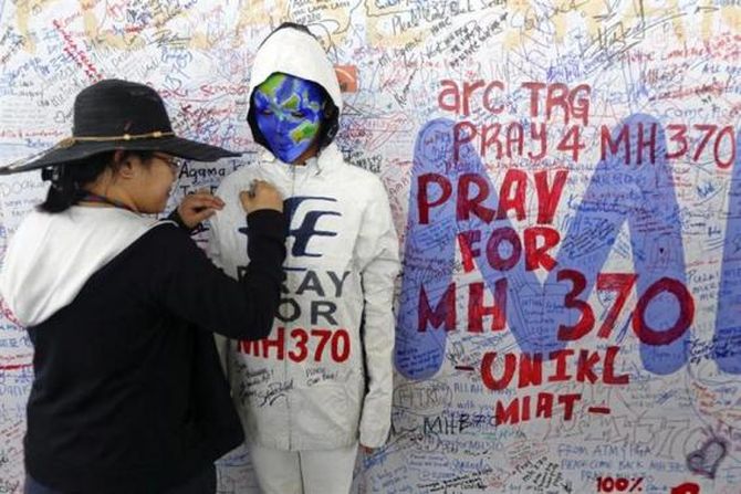 A woman adds her message on the clothes of a model during an art performance in support of the passengers of the missing Malaysia Airlines MH370 at the departure hall of Kuala Lumpur International Airport March 17, 2014.