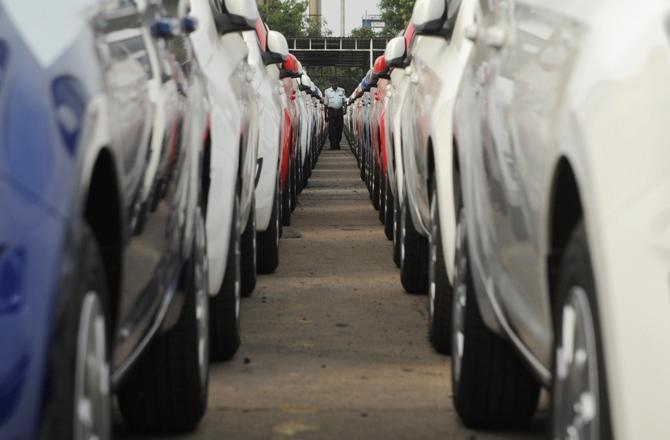 An employee walks between parked Hyundai cars ready for shipment at a port in Chennai.