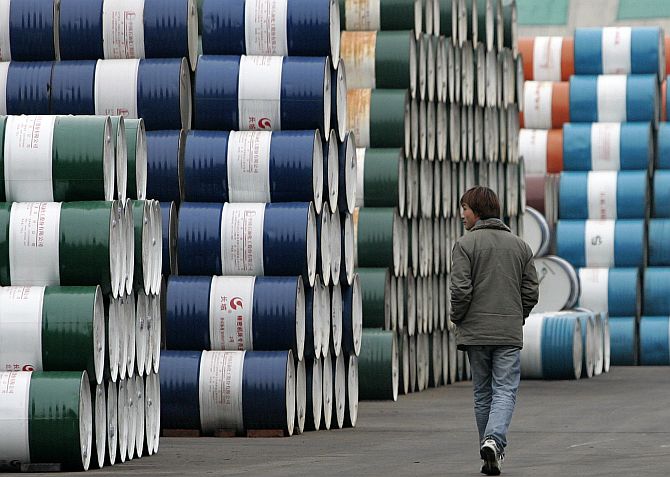 A man walks past a storage area for oil barrels in Shanghai.