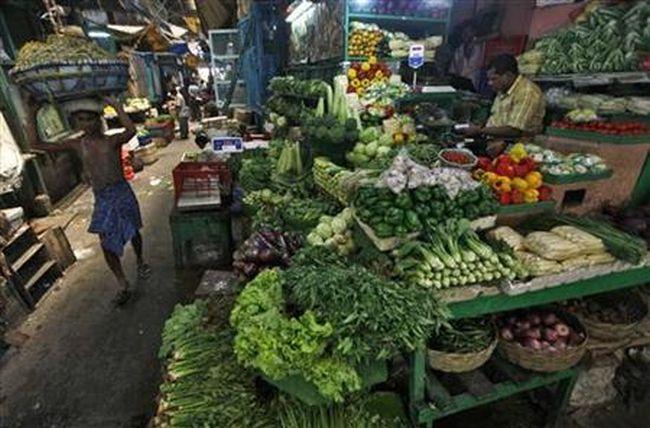 A labourer carries a packed basket of vegetables as a vendor waits for customers at his vegetables stall at a market in Kolkata May 14, 2012. 