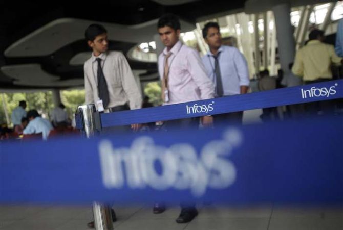 Employees of Indian software company Infosys walk past Infosys logos at their campus in the Electronic City.