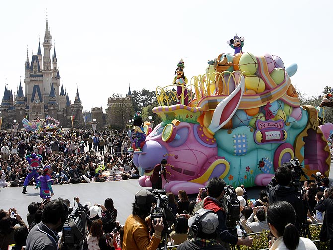 Disney character Mickey Mouse (top) performs atop a float during a parade at Tokyo Disneyland.