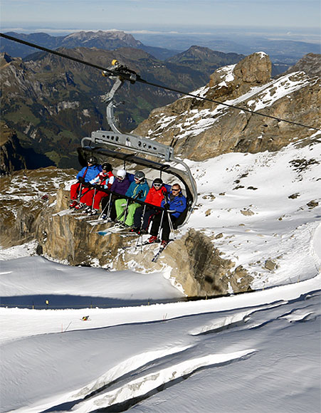 Skiers sit in a chairlift at the Mount Titlis skiing area (3,238 m/10,623 ft) near the Swiss mountain resort of Engelberg.