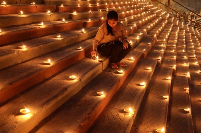 A Hindu devotee lights an earthen lamp on the steps of Sindhiya Ghat during the Karthik Purnima and Dev Diwali festival in Varanasi.