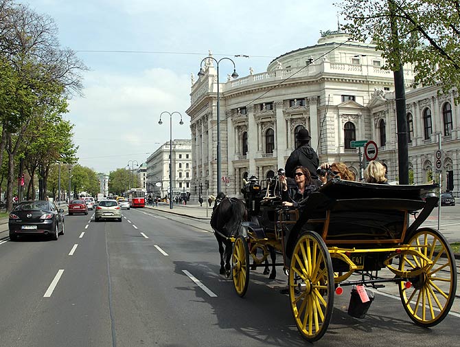 A traditional Fiaker horse carriage passes Burgtheater theatre on Dr.-Karl-Lueger-Ring street in Vienna.