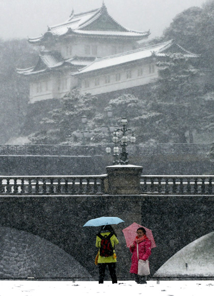 Visitors take photos at the Imperial Palace as snow falls in Tokyo.