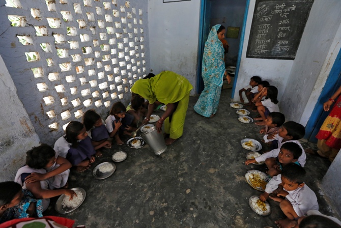 A cook serves the free mid-day meal, distributed by a government-run primary school, to children at Brahimpur village in Chapra district of Bihar.