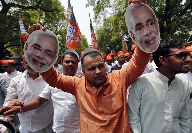 A supporter of India's main opposition BJP holds cut-outs of their prime ministerial candidate Narendra Modi.