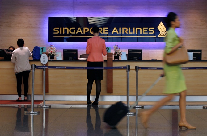 People walk past a Singapore Airlines ticketing counter at Changi Airport in Singapore.
