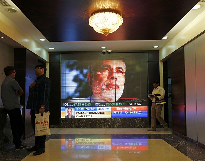 People look at a screen displaying the election results coverage on a screen inside the Bombay Stock Exchange (BSE) building in Mumbai.