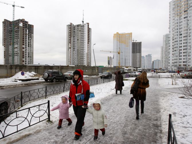 People walk in a residential district dotted with unfinished apartment buildings in Kiev D.