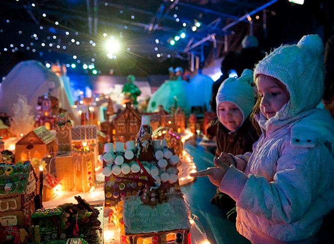 Children look at a gingerbread town consisting of buildings, boats, bridges and other structures, in Bergen.
