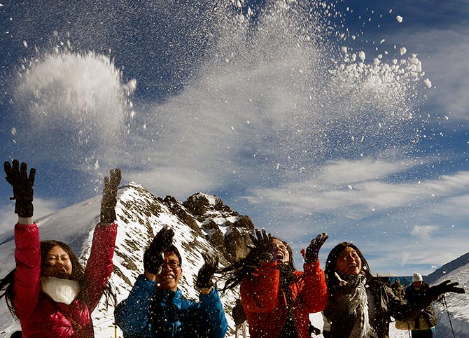 Tourists from Singapore throw up snow as they pose for a photograph in front of Mount Titlis.
