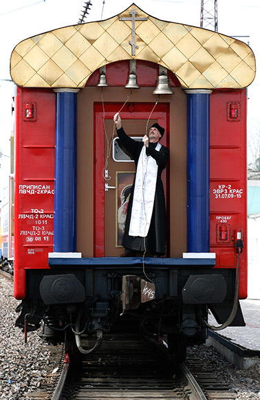An Orthodox priest rings the bells on the church carriage of the Doctor Voino-Yasenecky Saint Luka train.