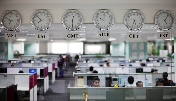 Workers are pictured beneath clocks displaying time zones in various parts of the world at an outsourcing centre in Bengaluru.
