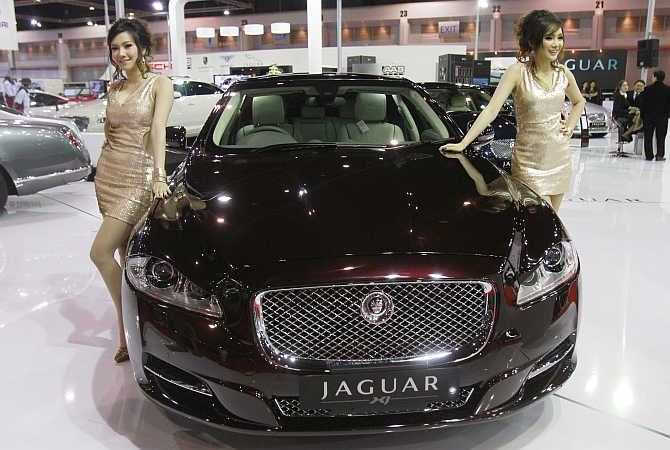 Models pose beside a Jaguar XJ in Bangkok, Thailand.