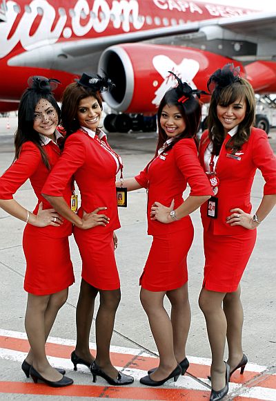 Stewardesses pose in front of an Airbus A340 passenger jet.