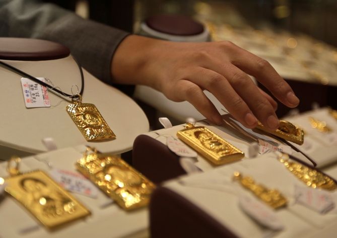 A sales assistant puts back a gold Buddha-shaped pendant after showing to a customer at Caibai Ornaments store in Beijing.