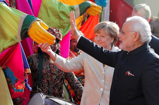 German Chancellor Angela Merkel and Prime Minister Narendra Modi (R) gesture to participants of the opening ceremony of Hannover Messe, in Hanover April 12, 2015. Wolfgang Rattay/Reuters