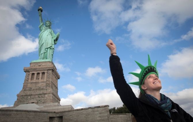 A tourist poses like the Statue of Liberty. 