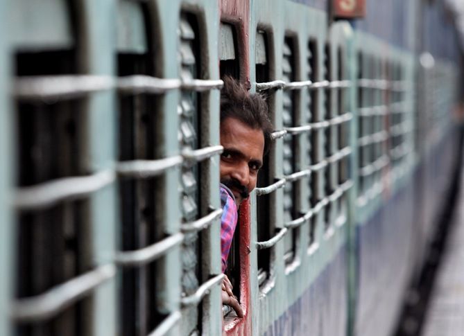 A passenger looks out from the window of a stationed train at a railway station in Jammu.