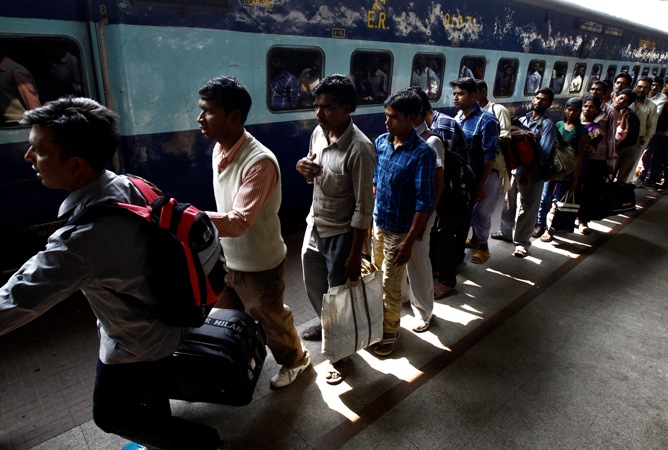 Commuters line up to board a passenger train at a railway station in Kolkata.