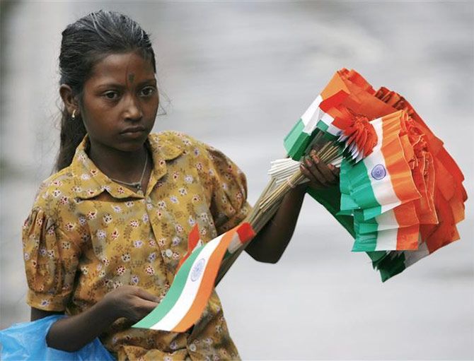 A girl sells Indian flags on an Indian street.